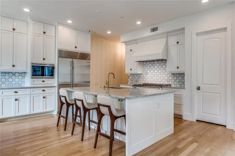 a kitchen with stainless steel appliances granite countertop a white cabinets and wooden floor