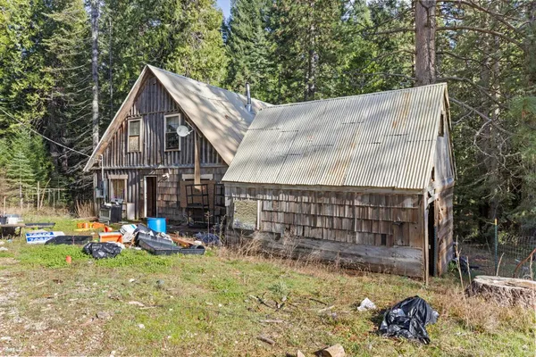 a view of a wooden house with a yard and large tree