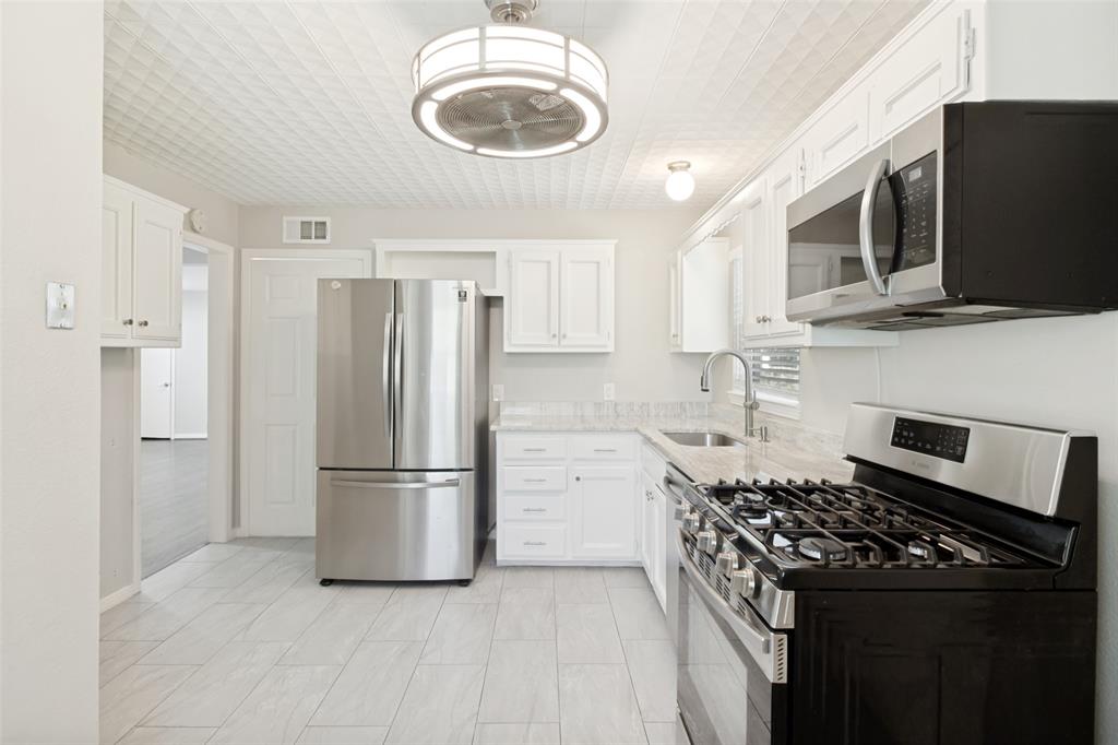 11524 Strand Street Dallas, TX 75218 - Photo 9 of 19 a kitchen with stainless steel appliances a stove a refrigerator and a microwave