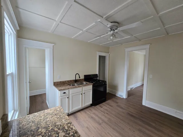 a kitchen with granite countertop a sink cabinets and wooden floor