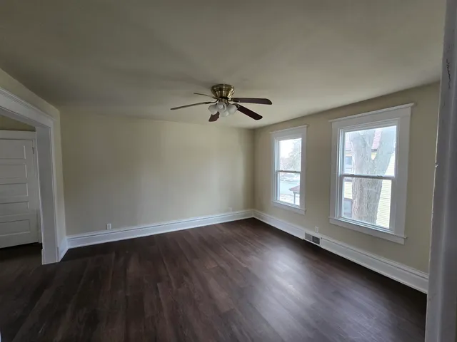 a view of empty room with wooden floor and fan