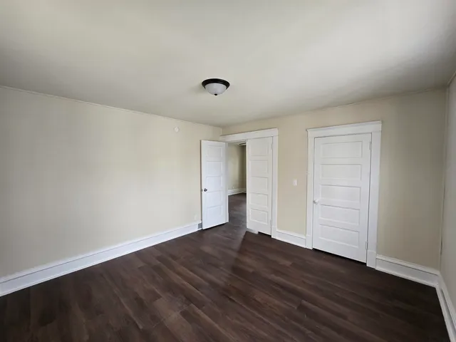 a view of an empty room with wooden floor and closet