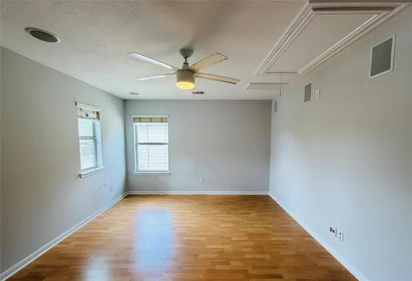 a view of empty room with wooden floor and fan