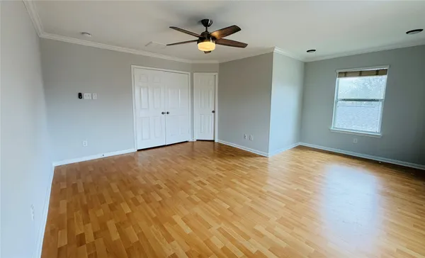 a view of empty room with wooden floor and fan