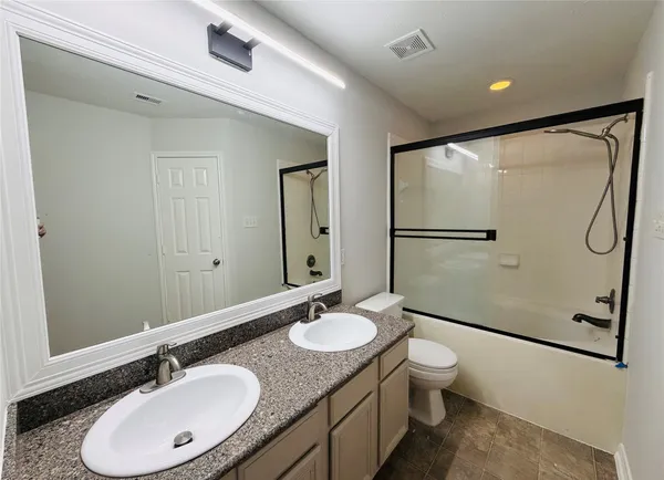 a bathroom with a granite countertop sink toilet a mirror and shower