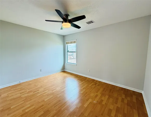 an empty room with a window and ceiling fan