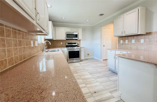 a kitchen with stainless steel appliances kitchen island granite countertop a sink a stove top oven a chimney and cabinets