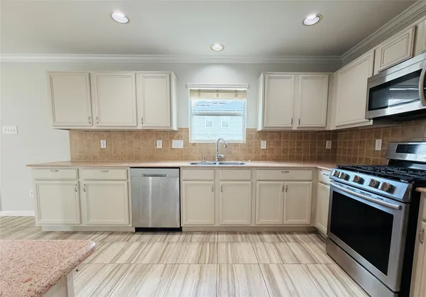 a kitchen with granite countertop a sink cabinets stainless steel appliances and a window