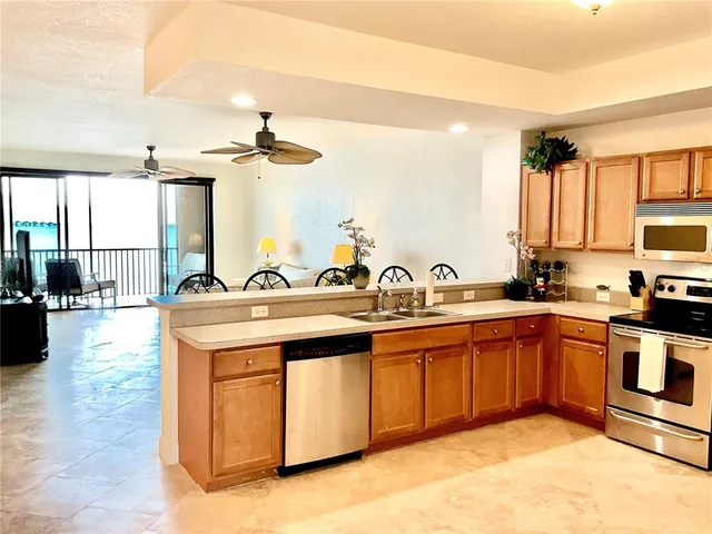 a kitchen with stainless steel appliances granite countertop a stove a refrigerator a sink a dining table and chairs