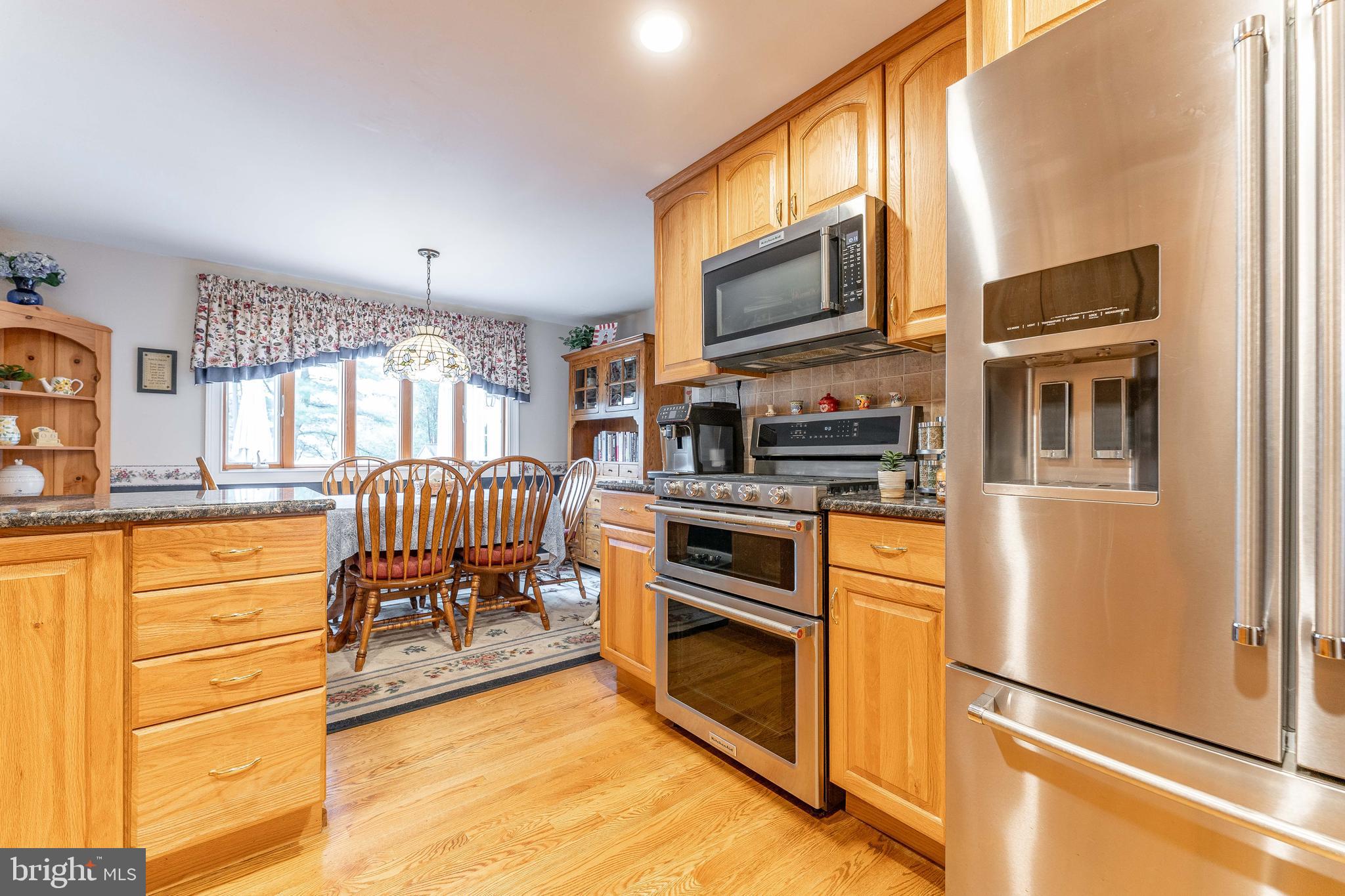 209 Beechtree Drive Broomall, PA 19008 - Photo 24 of 61 a kitchen with stainless steel appliances granite countertop a stove top oven a sink dishwasher a dining table and chairs with wooden floor