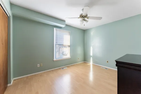 an empty room with wooden floor fan and windows