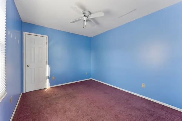 an empty room with a chandelier fan and windows