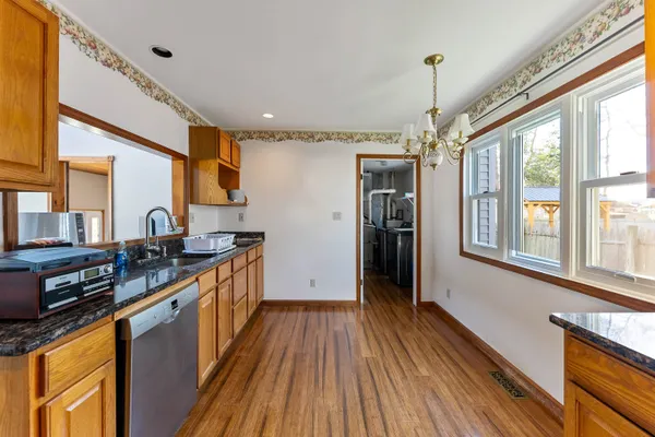 a kitchen with stainless steel appliances granite countertop a refrigerator a sink dishwasher a stove and white countertops with wooden floor