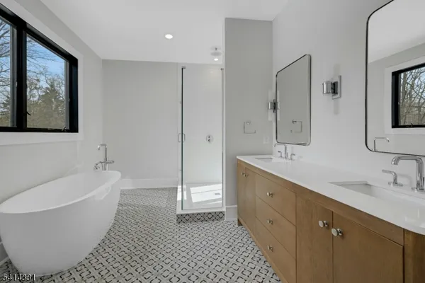 a spacious bathroom with a double vanity sink mirror and bathtub