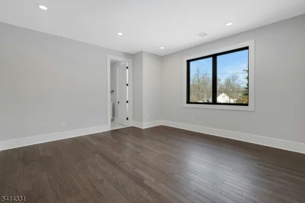a view of an empty room with wooden floor and painting on the wall