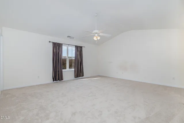an empty room with a window and a ceiling fan