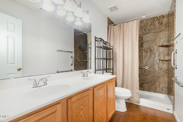a spacious bathroom with a sink toilet double vanity and shower