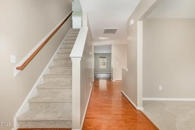 a view of a hallway with wooden floor and staircase