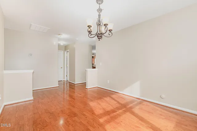 a view of an empty room with a chandelier fan