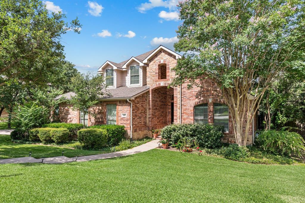 808 Briar Ridge Drive Keller, TX 76248 - Photo 2 of 40 Traditional brick facade residence with a prominent arched entry, multiple dormer windows, a concrete walkway, established landscaping, and a manicured lawn