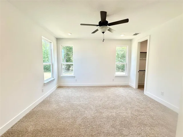 an empty room with ceiling fan and window