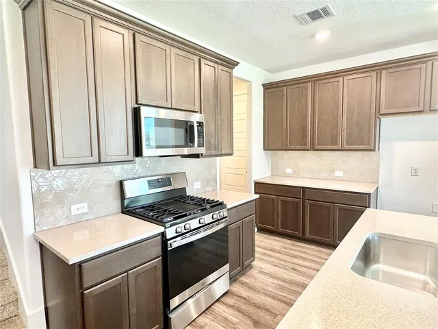 a kitchen with granite countertop a sink stove and microwave