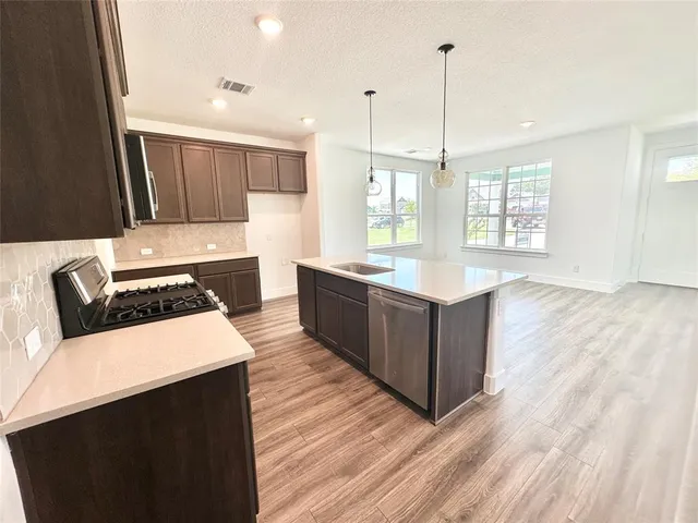 a kitchen with stainless steel appliances granite countertop a sink a stove and a wooden floors