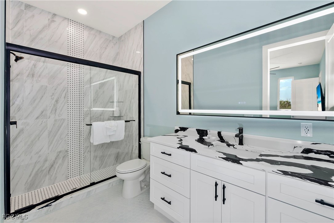 151 Chapel Street Fort Myers Beach, FL 33931 - Photo 21 of 23 a bathroom with a granite countertop sink a toilet a mirror and shower