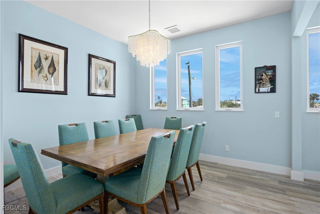 151 Chapel Street Fort Myers Beach, FL 33931 - Photo 5 of 23 a view of a dining room with furniture wooden floor and a chandelier