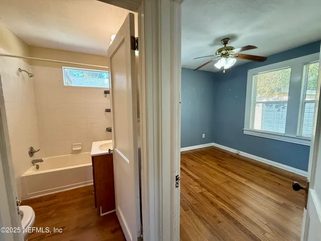 a view of a livingroom with wooden floor and a ceiling fan
