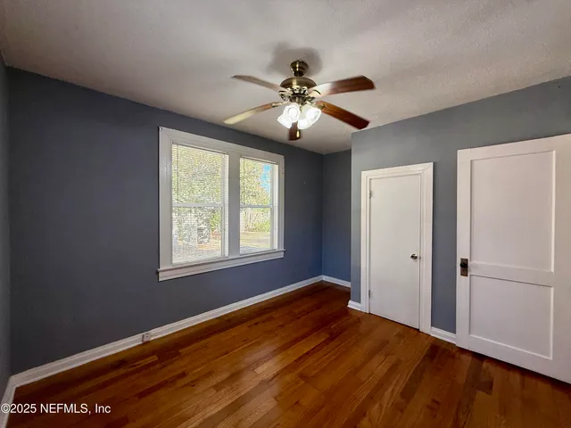 a view of empty room with wooden floor and fan