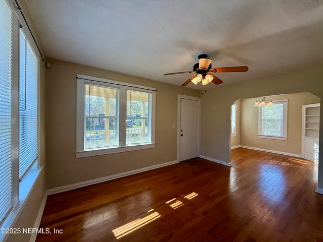 a view of an empty room with wooden floor and a window
