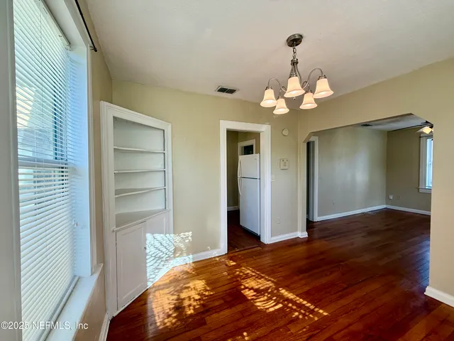 a bedroom with wooden floor closet and a chandelier