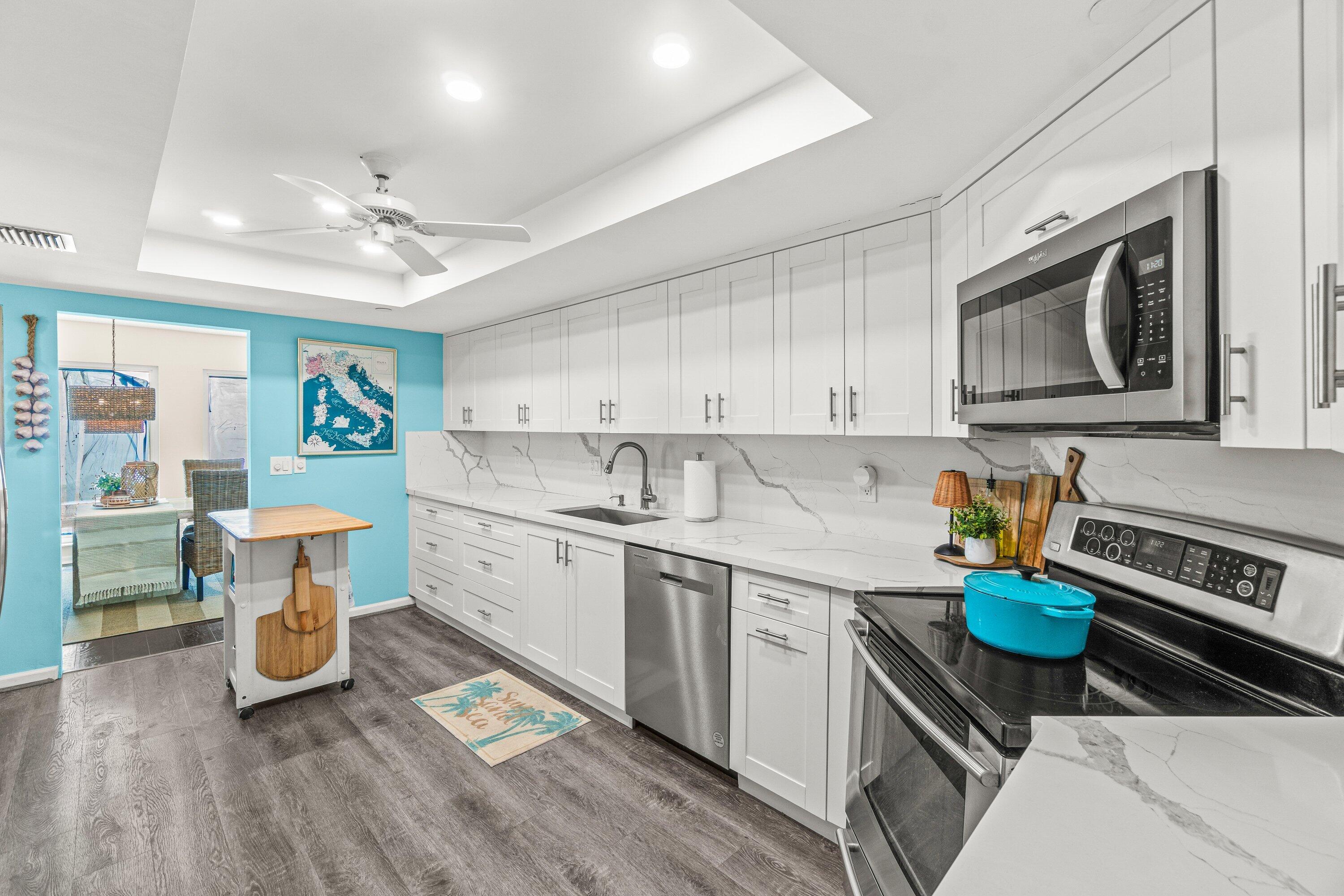 4301 North Ocean Boulevard, Unit 708 Boca Raton, FL 33431 - Photo 20 of 51 a kitchen with stainless steel appliances a stove a sink cabinets and a wooden floor