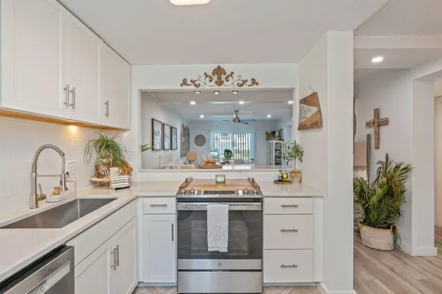 a kitchen with kitchen island white cabinets and stainless steel appliances