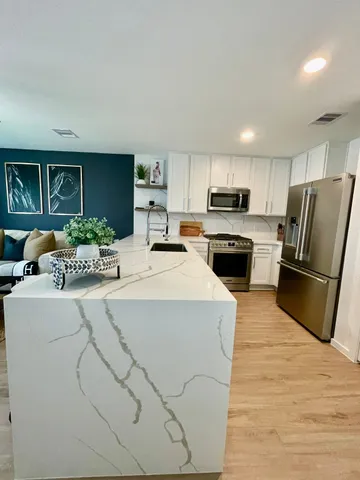 a kitchen with stainless steel appliances a stove refrigerator sink and a refrigerator