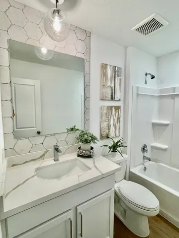 a bathroom with a double vanity sink toilet mirror and bathtub