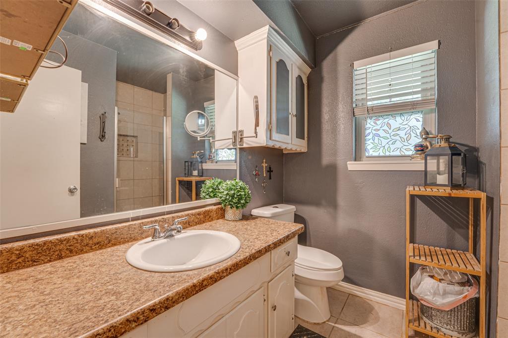 903 Walnut Street Royse City, TX 75189 - Photo 17 of 28 a bathroom with a granite countertop toilet a sink and a mirror