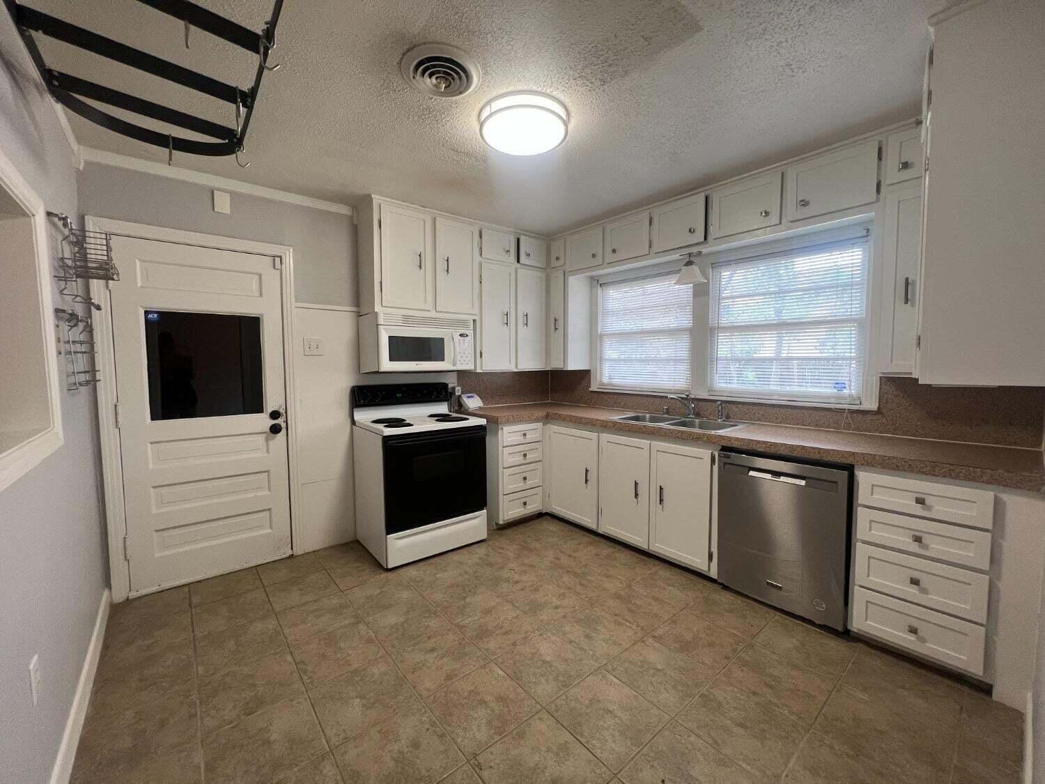 2314 35th Street Lubbock, TX 79412 - Photo 4 of 9 a kitchen with granite countertop white cabinets and white appliances