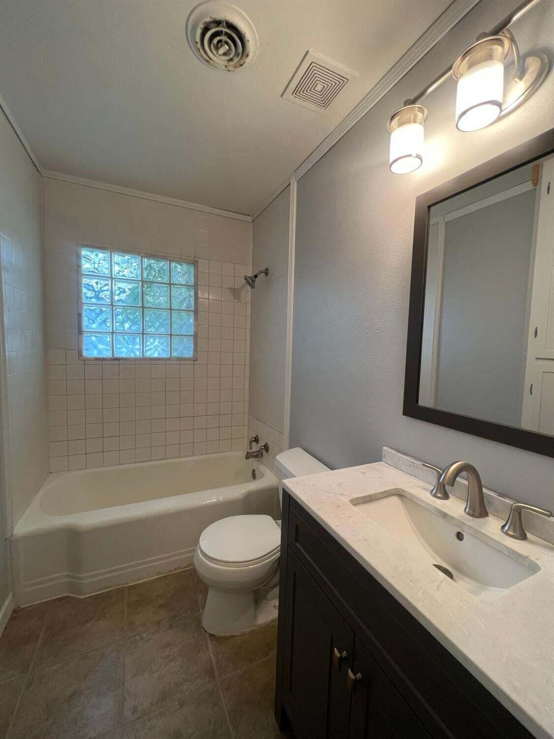 2314 35th Street Lubbock, TX 79412 - Photo 7 of 9 a bathroom with a granite countertop sink toilet and shower