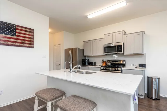 a kitchen with stainless steel appliances granite countertop a refrigerator a stove a sink a dining table and chairs