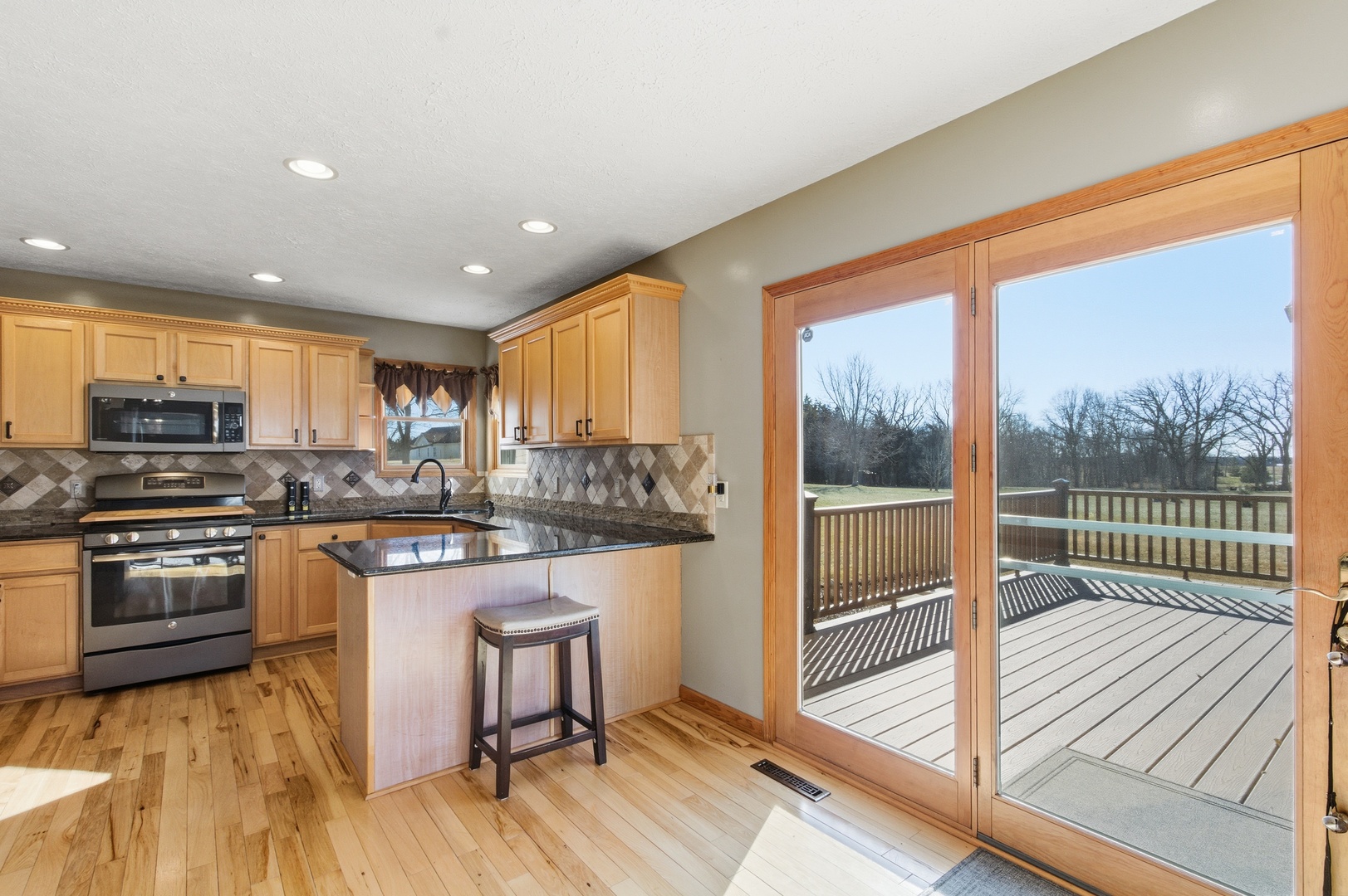 2216 North 2929th Road Marseilles, IL 61341 - Photo 14 of 49 a kitchen with stainless steel appliances granite countertop a refrigerator a stove top oven and a large window with wooden floor