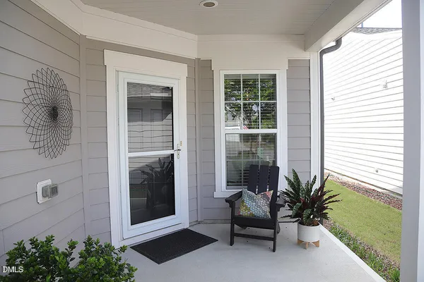a porch with a bench and potted plant