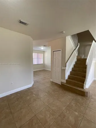 a view of an empty room with stairs and a window