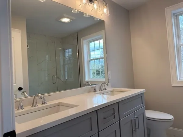 a bathroom with a granite countertop sink a toilet and a mirror