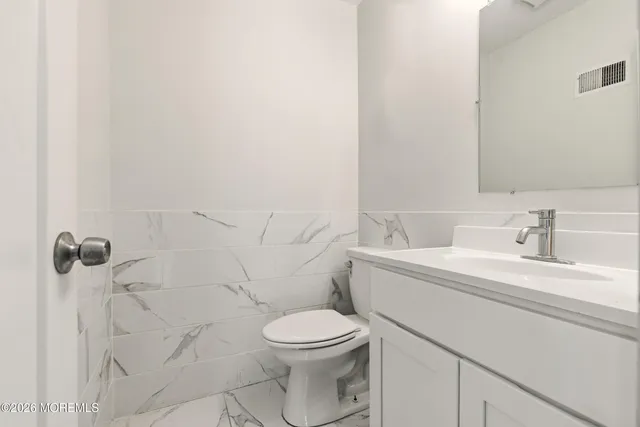 a bathroom with a toilet a sink a mirror and vanity