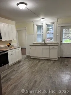 a large kitchen with granite countertop a sink and white cabinets
