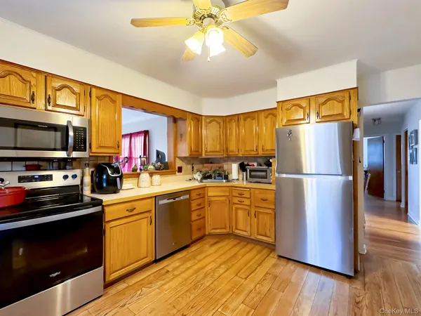 a kitchen with stainless steel appliances granite countertop a refrigerator a stove top oven a sink and dishwasher with wooden floor