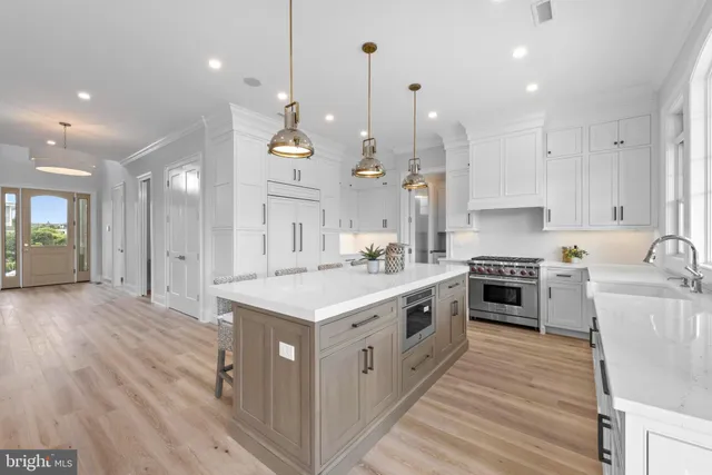 a kitchen with stainless steel appliances granite countertop a refrigerator a stove and white cabinets with wooden floor