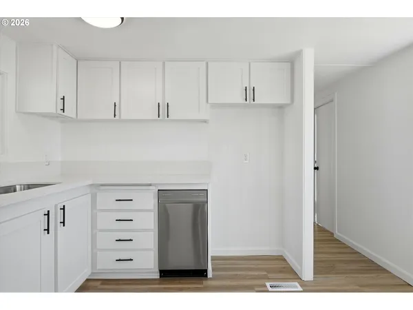 a kitchen with white cabinets and a wooden floor